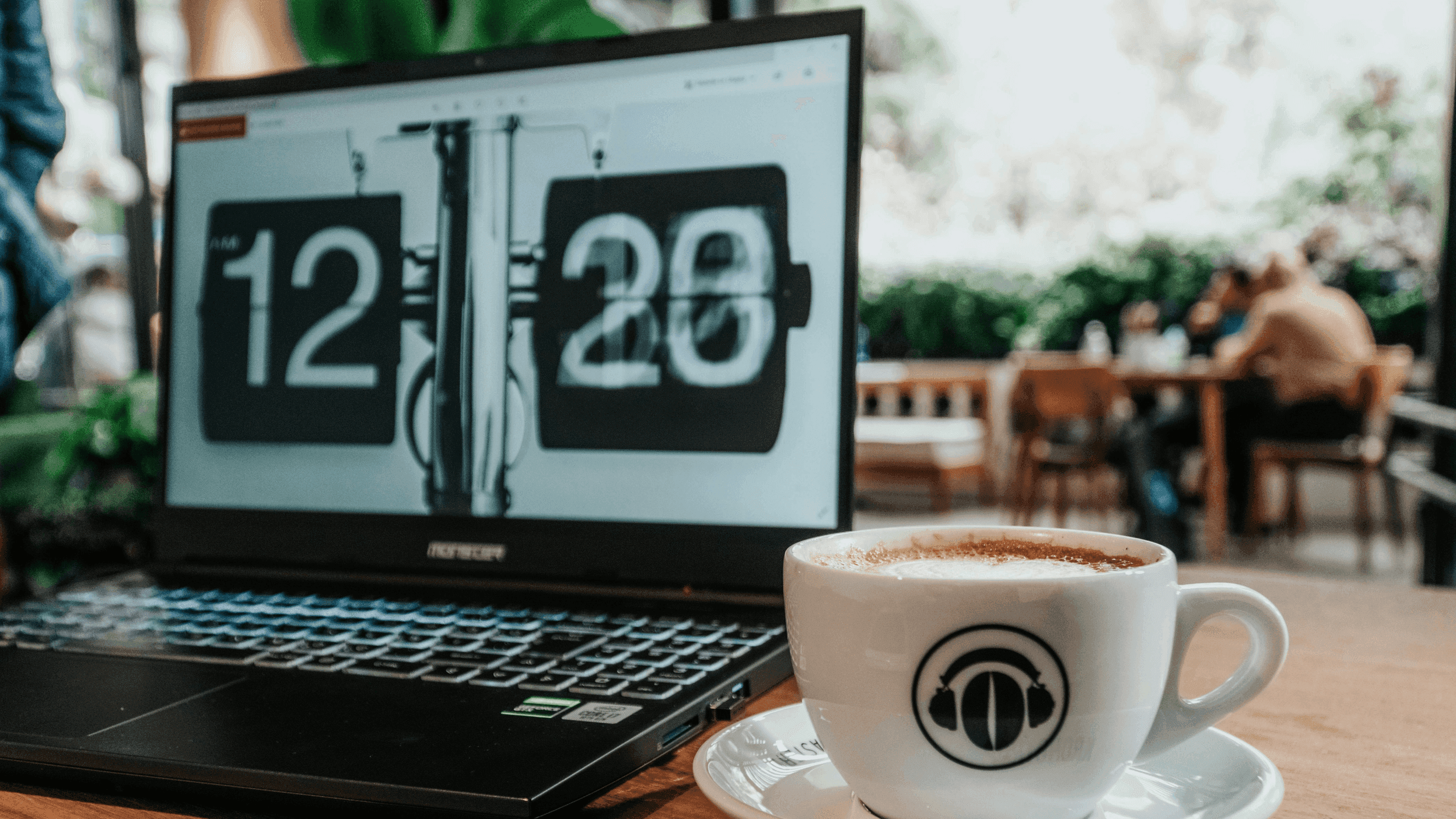 Laptop on a table beside a coffee cup