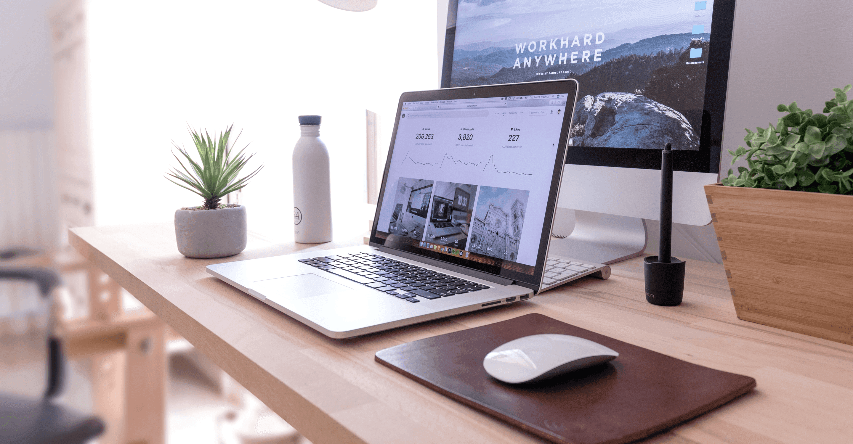 Modern desk setup with a laptop, monitor, keyboard, and accessories